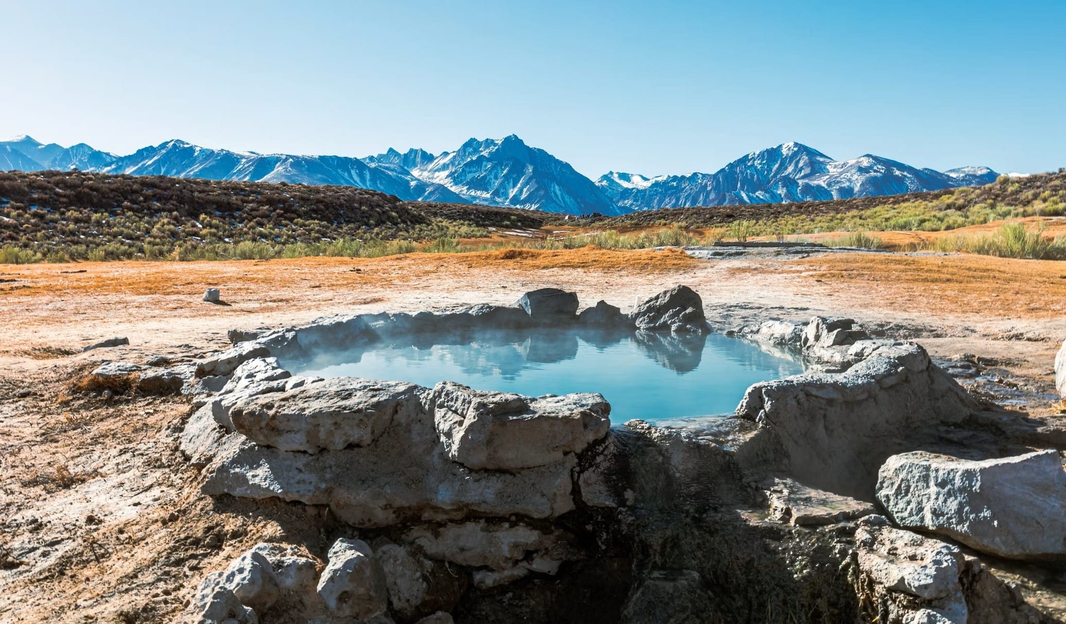 Natural hot spring pool with mountain backdrop